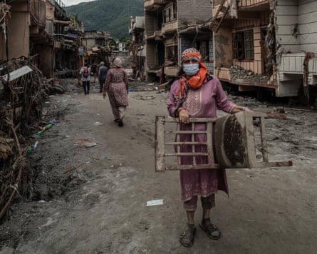 Woman on muddy street carrying a chair