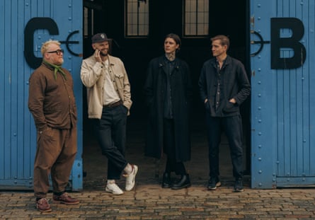 Four people standing outside warehouse doors