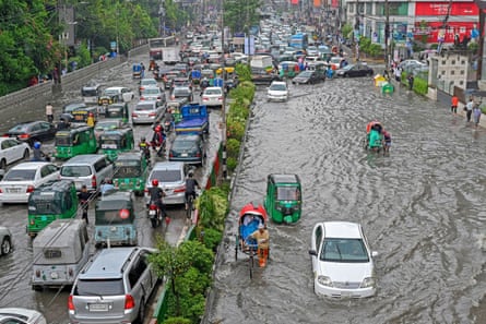 Rickshaw drivers and cars struggle in flooded streets