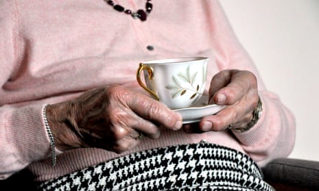 An elderly woman holding a cup and saucer