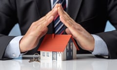 A man in a suit putting tented hands over a toy house