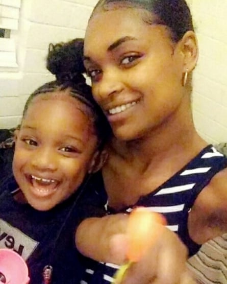 A young Black woman cuddling with a young Black girl, both smiling happily. A young Black woman cuddling with a young Black girl, both smiling happily.