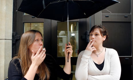 two women smoking under an umbrella