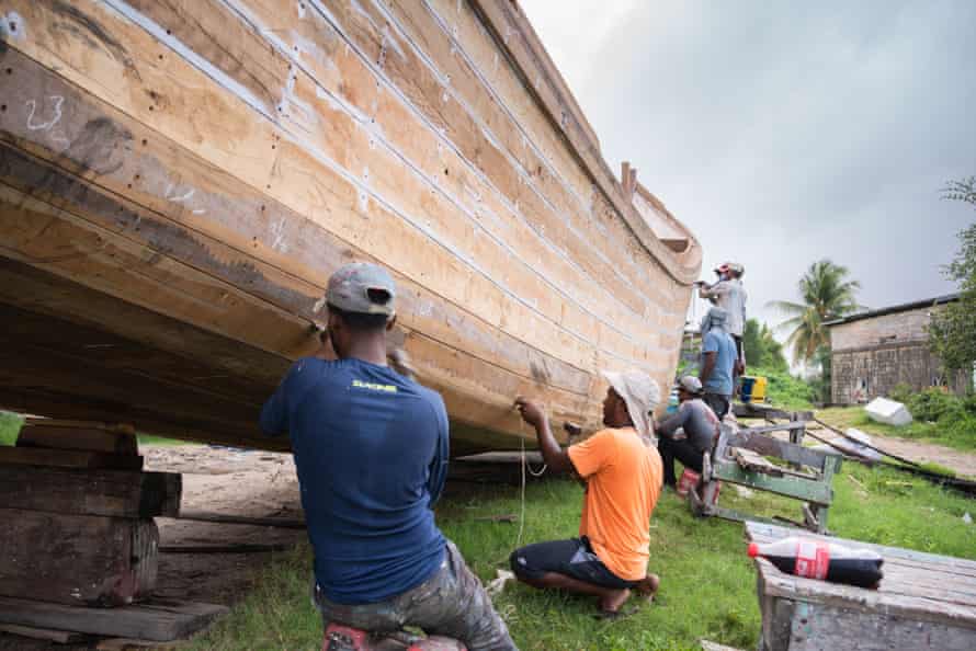 Men sealing joints on boats they are building