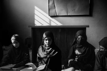 A group of girls sitting at desks with books in front of them