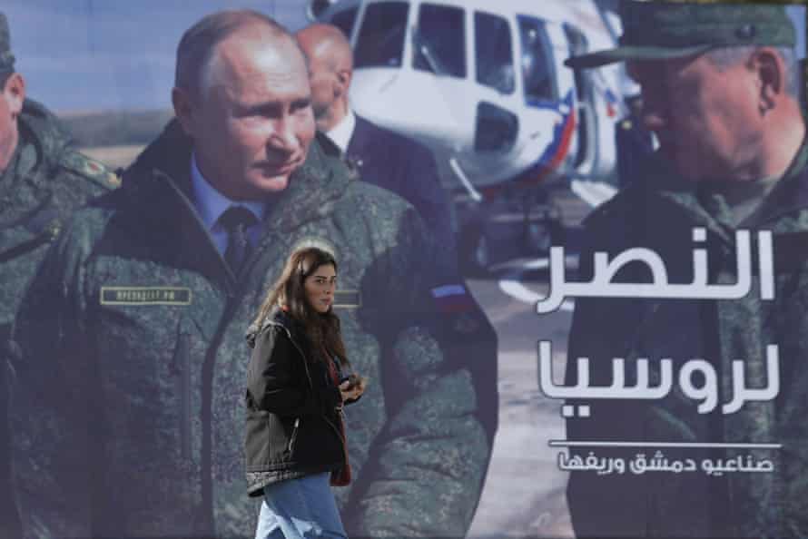 A woman passes a billboard showing Russian president Vladimir Putin in Damascus, Syria, last year. The poster reads “ The victory for Russia.”