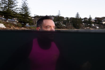 Graham Russell in a wetsuit and pink vest in the ocean with half his head underwater