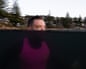 Graham Russell in a wetsuit and pink vest in the ocean with half his head underwater