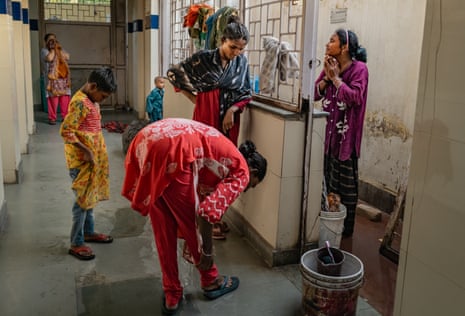 Women stand in a corridor adjusting their clothing