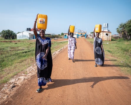Nyandong Chang (left), 28, and two friends carry water from a water kiosk to their homes in Bor, South Sudan, on 6 November 2025