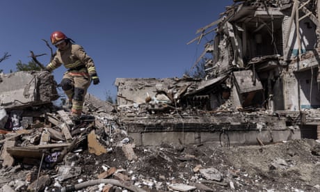 A firefighter climbs down the face of a destroyed building after a Russian airstrike of the residential community of Pidhorodne in a town north of Dnipro, Ukraine, on Sunday