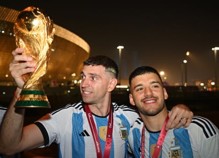 Emiliano Martínez holds the World Cup trophy alongside Geronimo Rulli outside the stadium after Sunday's match.