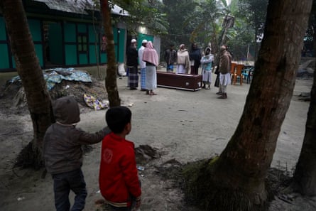 A group of mourners around a coffin at a funeral