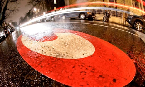 A close-up of the red and white  'C' roundel painted on London streets to warn motorists of the congestion charge zone