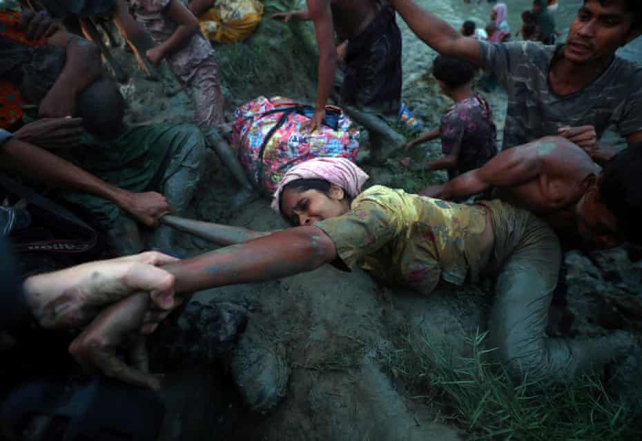 Photographers help a Rohingya woman out of the Naf river as refugees cross the Myanmar-Bangladesh border in Palong Khali, near Cox’s Bazar