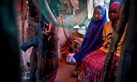 Two young girls with a security guard in their temporary shelter in a settlement for internally displaced people near the airport in Mogadishu.