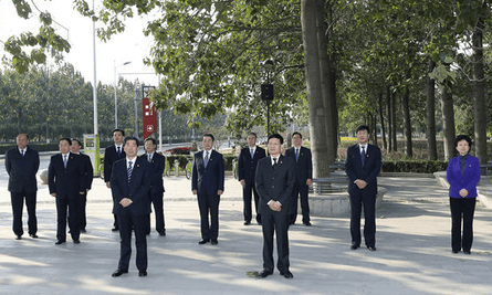 Officials stand in front of a tree which was planted by Chinese president Xi Jinping
