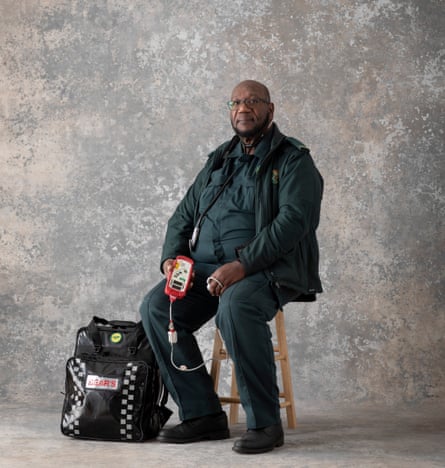 Glenn Carrington, paramedic, sitting on a stool and holding medical equipment