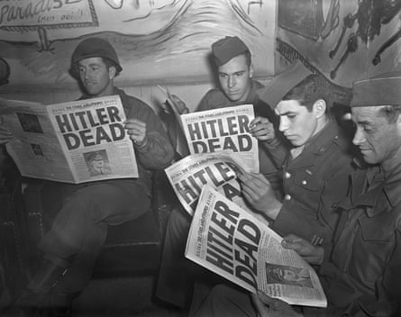 soldiers read newspapers with a front page headline that reads ‘Hitler dead’
