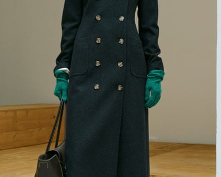 A model wears a long dark double-breasted coat with green gloves, from Ralph Lauren’s collection