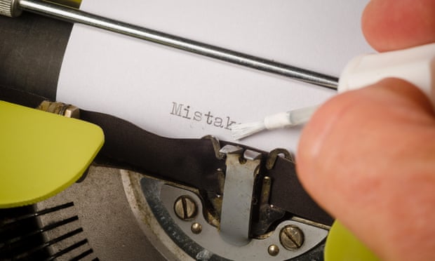 Ktoś używa płynu korekcyjnego, aby poprawić błędne słowo na kartce papieru w ręcznej maszynie do pisania