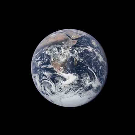 A full colour photograph of the Earth, with deep blue oceans, browmn continents and swirling white cloud, against an inky black backdrop
