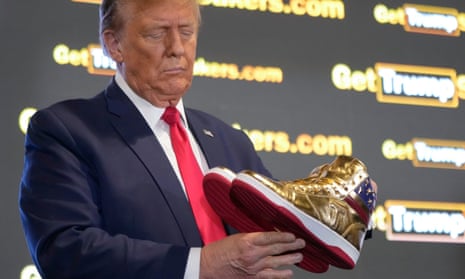 Republican presidential candidate and former president Donald Trump holds gold Trump sneakers at Sneaker Con Philadelphia.