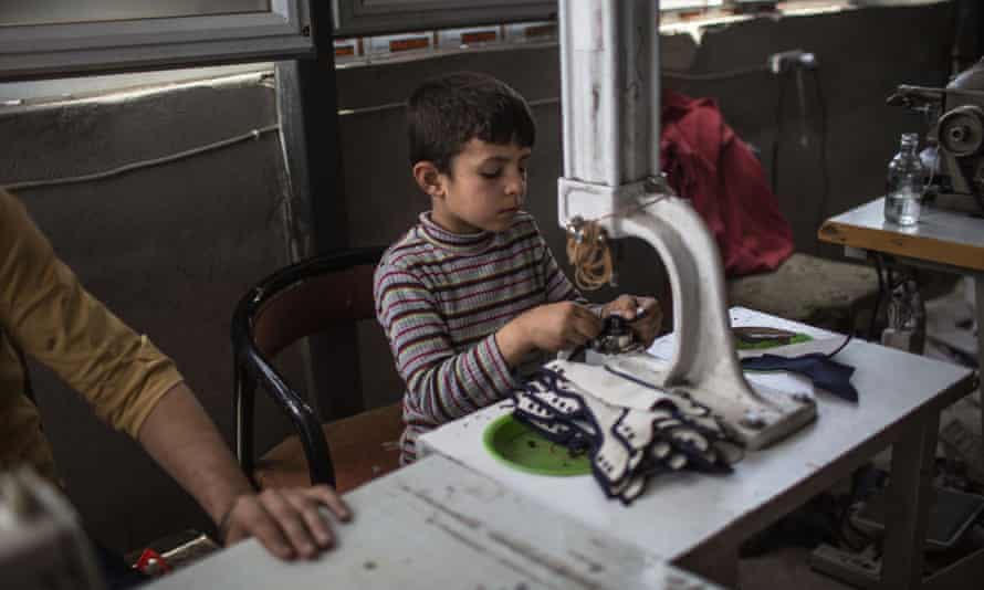 A small boy makes shoes in the factory