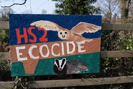 A sign on a fence with the words ‘HS2 ecocide’ and depictions of an owl and a badger
