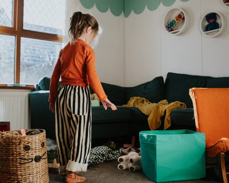 A little girl in an untidy playroom.