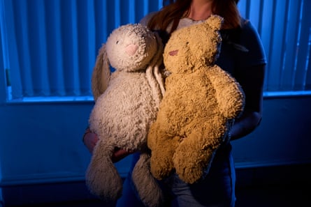 anonymised image of a woman holding two large soft toys, one a teddy bear and the other a rabbit-like creature.