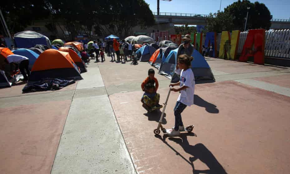 Children play next to migrants from Central America hoping to cross into the US, at their campsite outside El Chaparral border crossing, in Tijuana, Mexico, on 27 February.