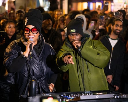 Jill Scott and DJ AG with microphones with a large crowd behind them