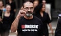 Andrew Malkinson, who wears glasses and has a beard, holding a fist in the air. He is wearing a black t-shirt reading: 'Innocent. And not the only one ..."
