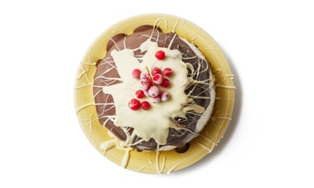 Bombe glacée, avec du chocolat blanc dégoulinant sur d'autres chocolats et des baies sur le dessus, vue de côté