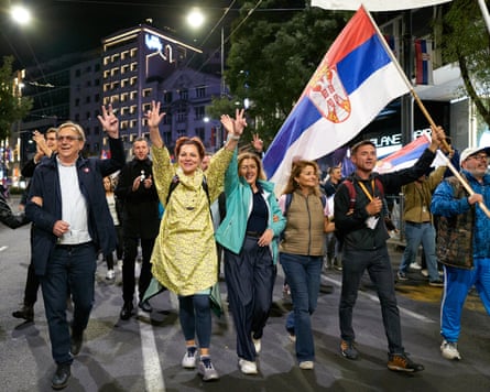 Student List supporters march through Belgrade at night, waving and carrying a Serbian flag