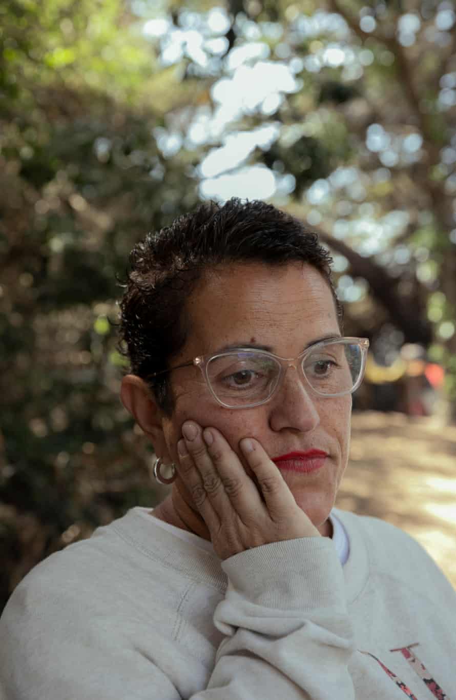 A woman with short hair and glasses rests her hands on her face