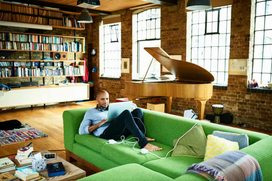 Man using laptop at home in apartment containing a grand piano