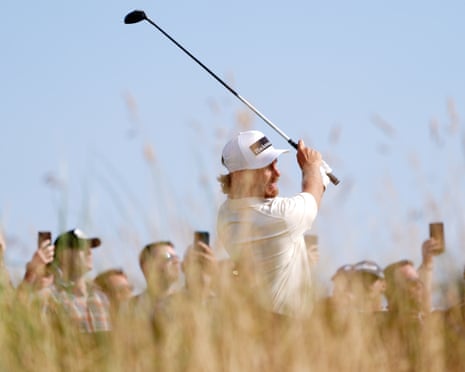 Tommy Fleetwood completes his follow-through swing with spectators watching in the background