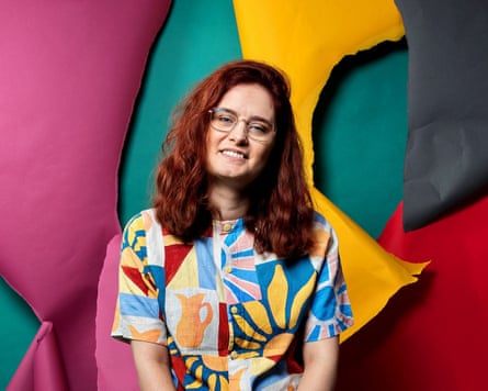She poses, smiling, against a multicoloured background