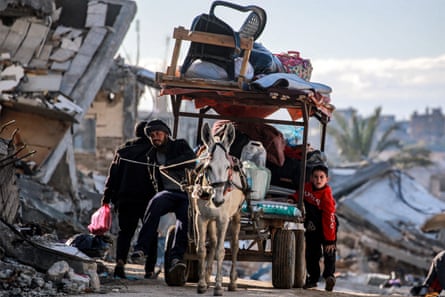 A donkey pulls a cart loaded up with belongings along a destroyed street in Gaza