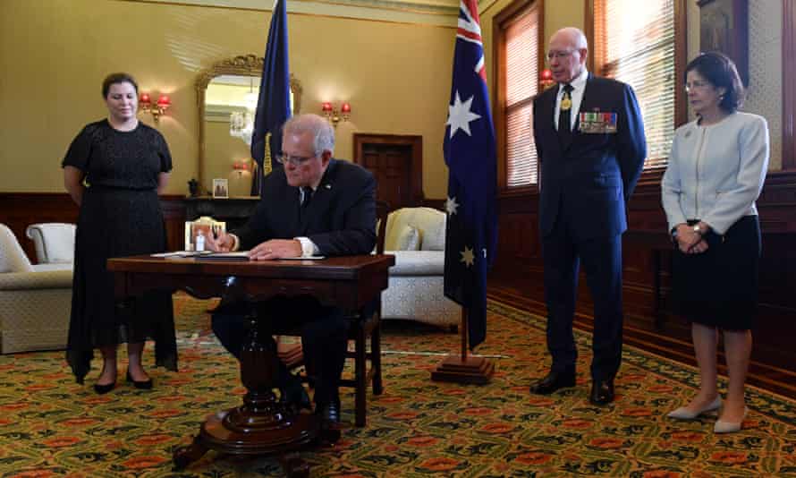 The Australian prime minister, Scott Morrison, signs a condolence book as his wife, Jenny, governor general David Hurley and his wife, Linda, look on.