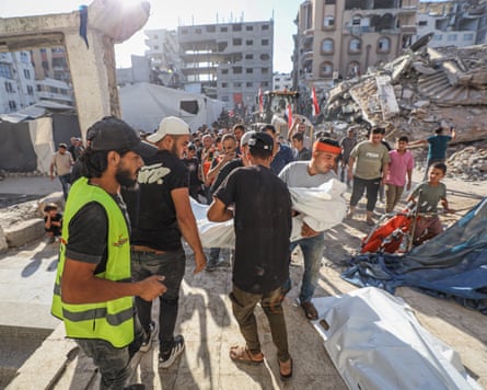 People carrying a body wrapped in a white sheet from the site of the catastrophe