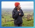 A woman wearing a black waterproof jacket and an orange beanie on a hill walk