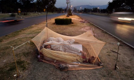 Pakistani labourers sleep under a mosquito net in the middle of a road in Islamabad.