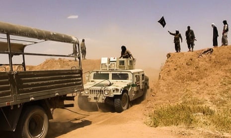 Isis militants waving a jihadi flag as vehicles drive on a new road through the Syrian-Iraqi border between the Iraqi Nineveh province and the Syrian town of Al-Hasakah, June 9 2014.