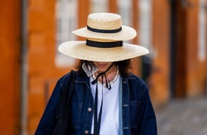 Copenhagen, Denmark. A wide-brimmed straw hat with another smaller straw hat on top obscures the face of a person wearing a light blue top under a dark blue jacket