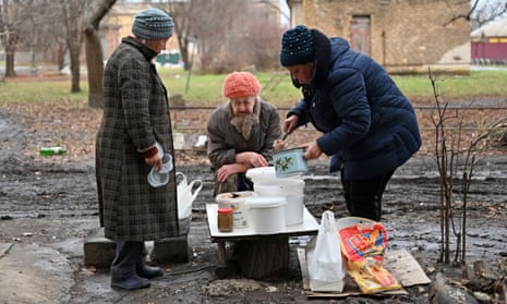 A local resident distributes to her neighbour’s hot food brought by volunteers in the yard of a residential building in the de-occupied town of Izyum, Kharkiv region.