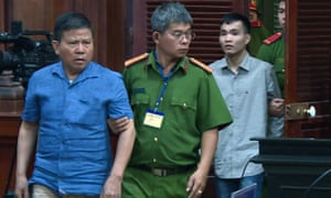 Chau Van Kham, left, is escorted to court in Ho Chi Minh City