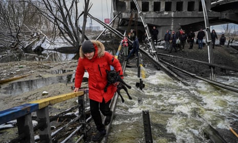 Civilians cross a river on a blown-up bridge in Kyiv, 1 March 2022